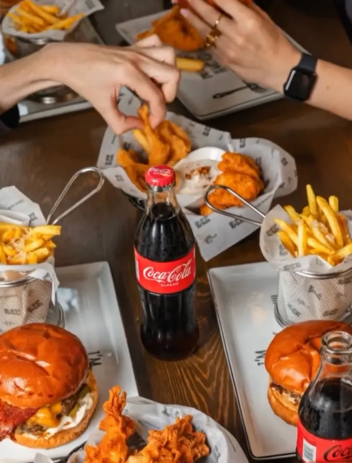 Friends grabbing crispy chicken and fries with Coca-Cola