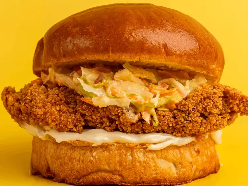 Bee Chick crispy fried chicken burger with coleslaw on yellow
