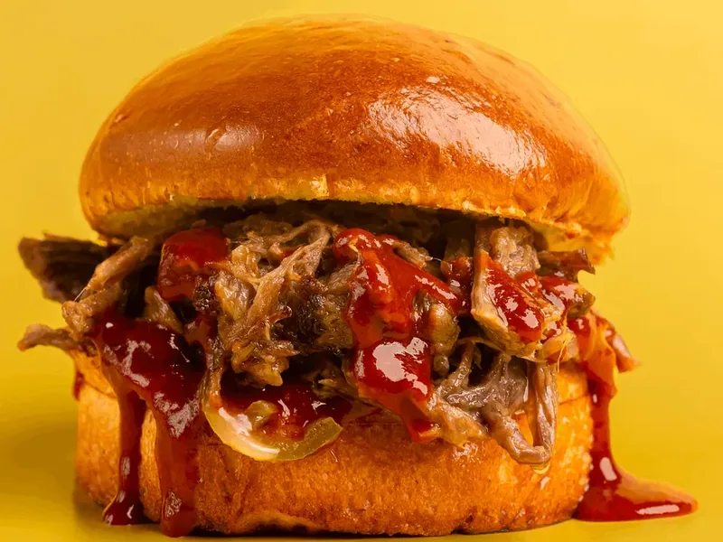 Acılı BBQ souslu, uzun bişirilmiş liflərə ayrılan dana ətli Tiftik burger, sarı fonda